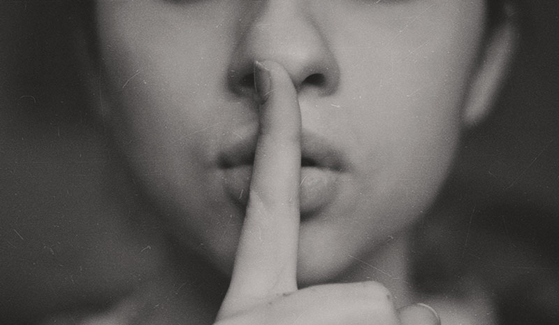 Photo of woman making the "Shh" sign - trust in marriage